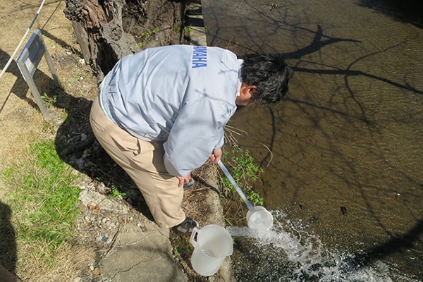 Yamaha staff conducting water quality inspection at a river.