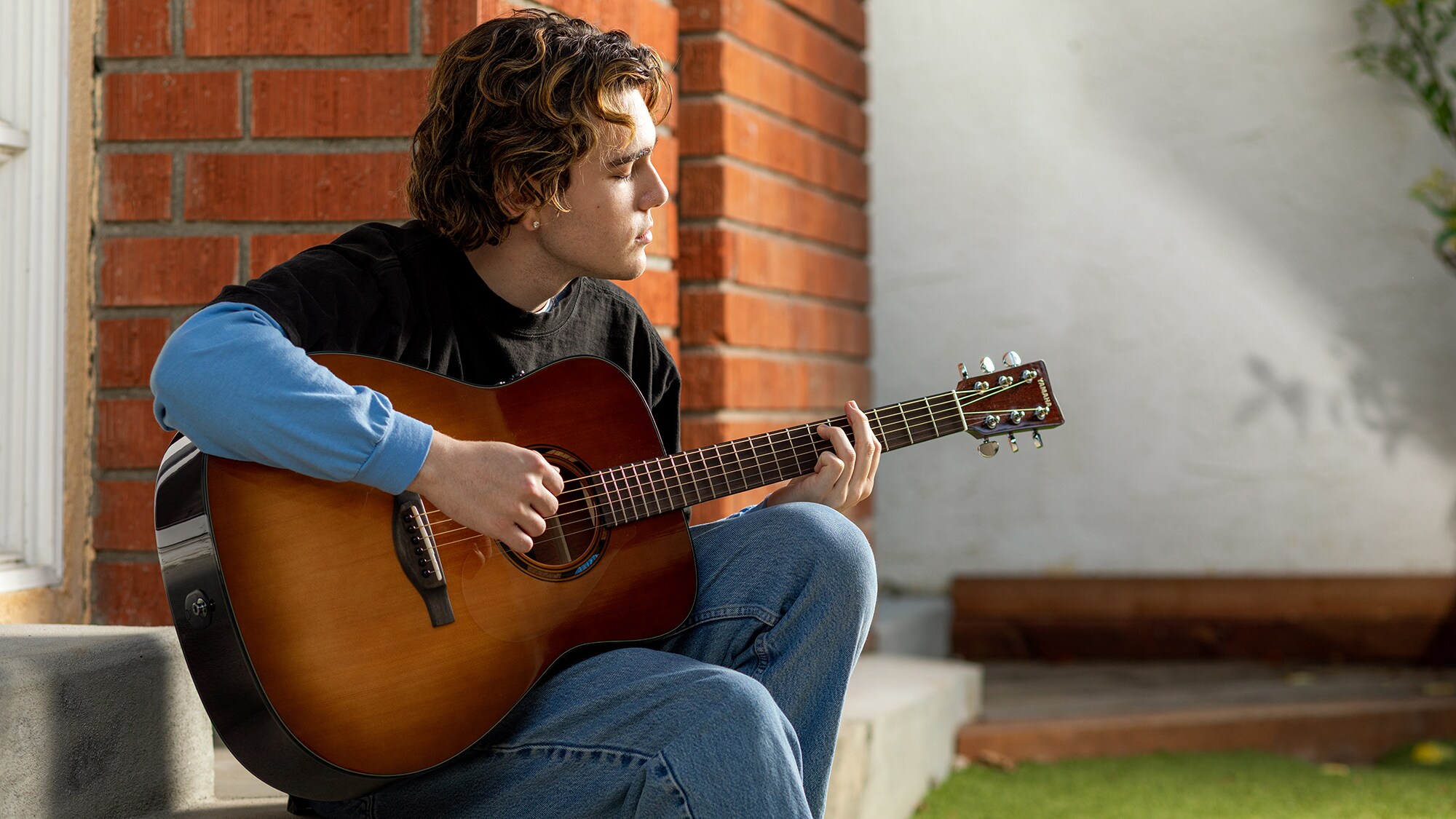 A man playing an TAG1 E acoustic guitar outdoors