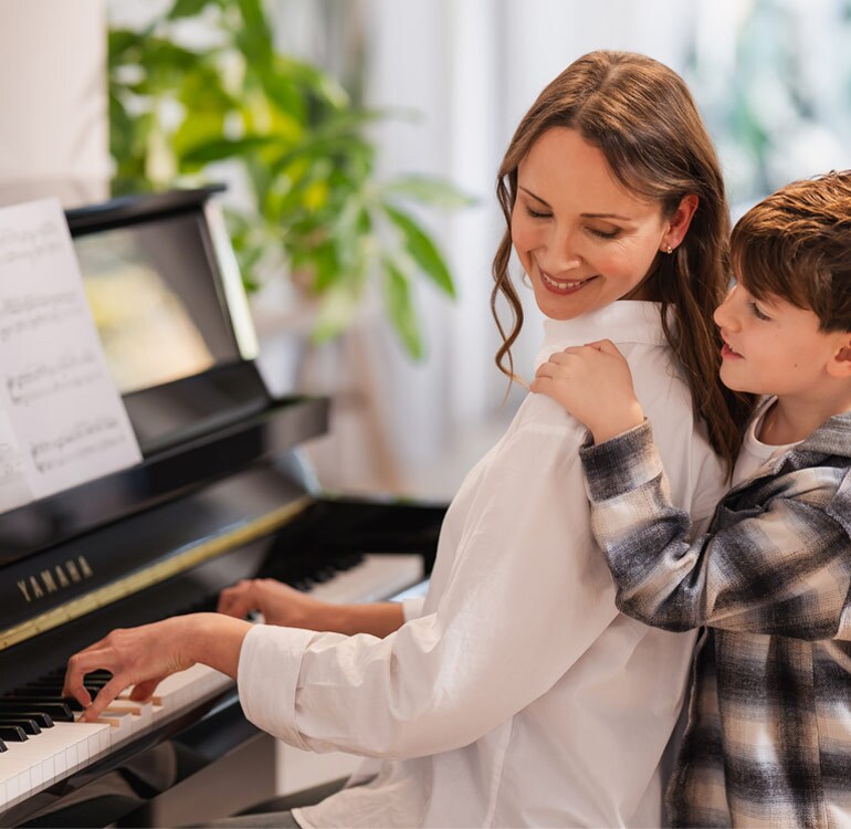 A mother and daugter enjoy playing the upright piano B series